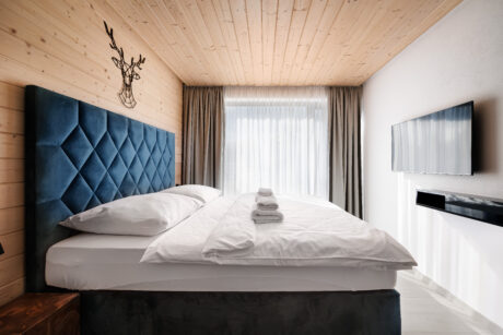 Pokój hotelowy z tapicerowanym łóżkiem boxspring i granatowym pikowanym wezgłowiem