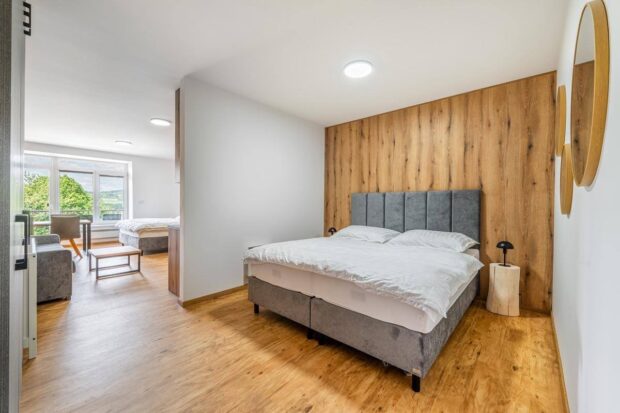 Moderní hotelový pokoj s manželskou postelí, dřevěným obkladem a výhledem