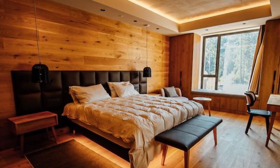 Moderní hotelová postel s čalouněným čelem a LED podsvícením v designovém hotelovém pokoji.